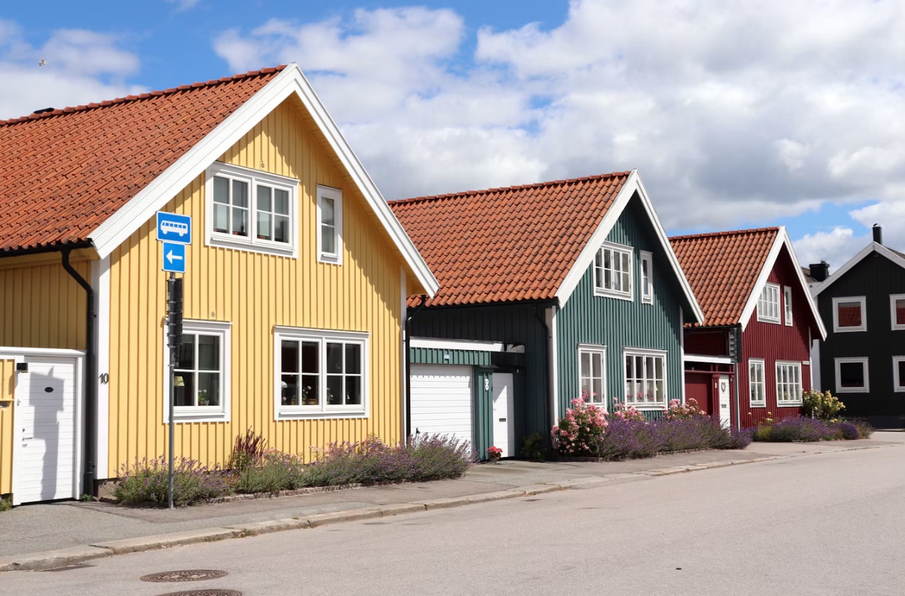 Trähus i gult, grönt och rött längs en villagata